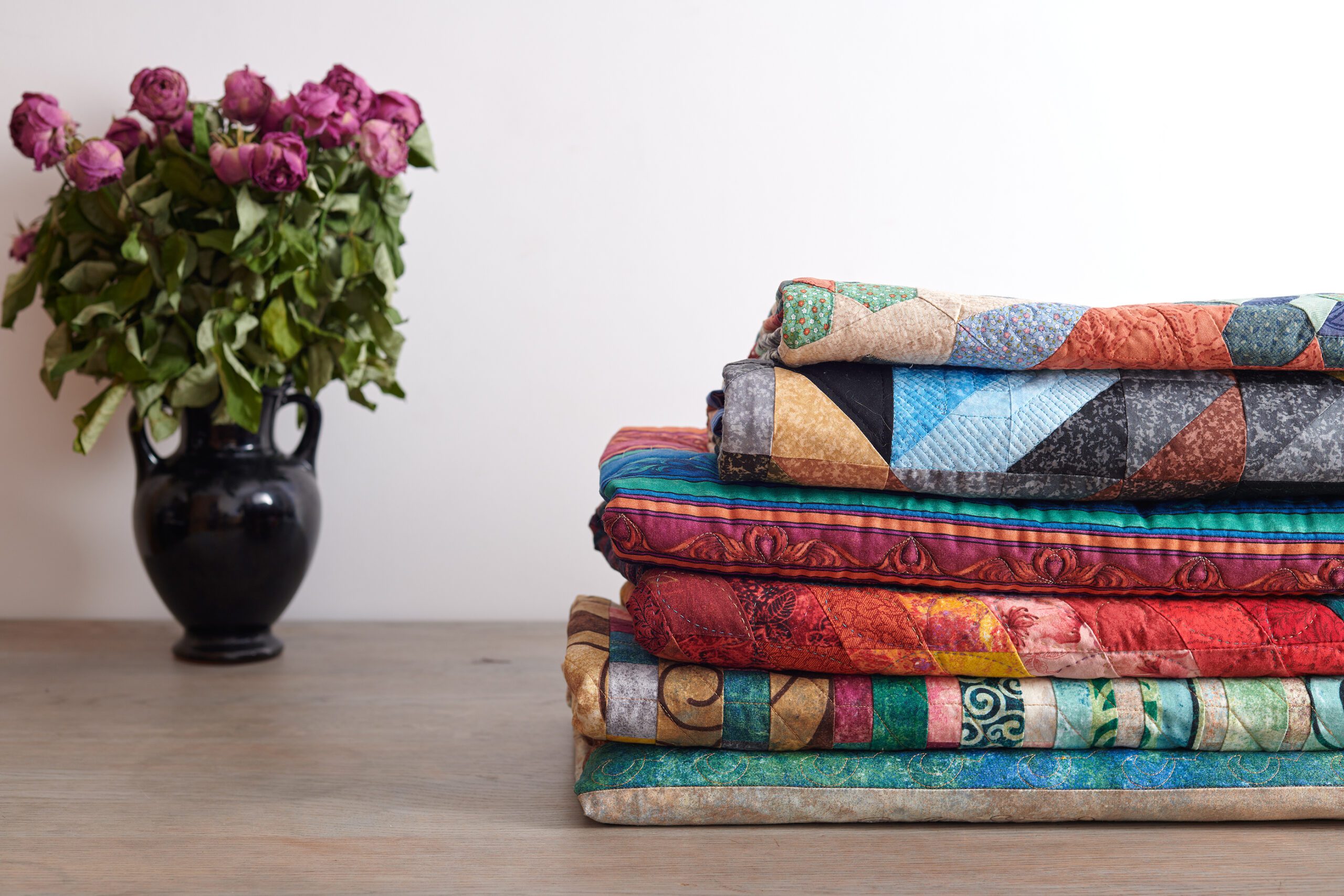 Quilts Stack And A Bouquet Of Dried Roses In A Vase On White Wal quilter's new year's resolution
